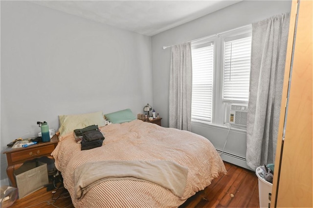 bedroom featuring cooling unit, a baseboard heating unit, and wood finished floors