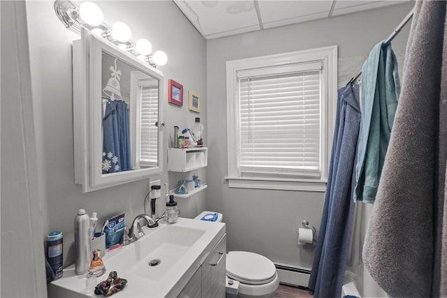 bathroom with vanity, a baseboard heating unit, a shower with curtain, toilet, and a drop ceiling