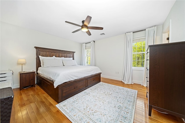 bedroom with baseboards, ceiling fan, light wood-style flooring, and visible vents
