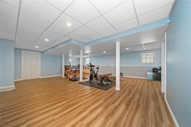 exercise area with recessed lighting, baseboards, a paneled ceiling, and light wood-style floors