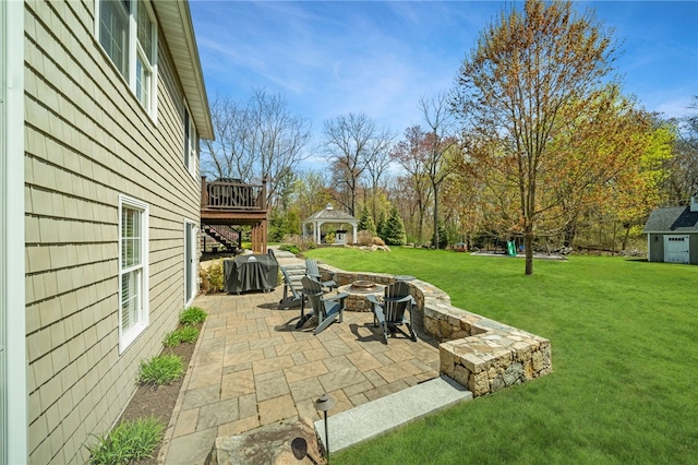 view of patio featuring grilling area, a wooden deck, a gazebo, and a fire pit