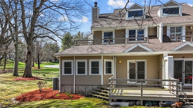 view of front of house featuring roof with shingles, a front lawn, cooling unit, a chimney, and a balcony