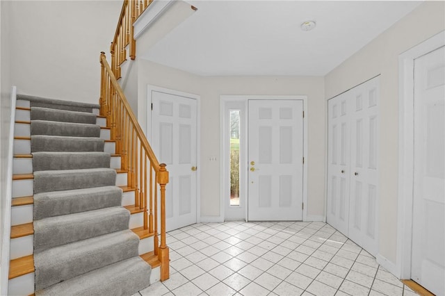 entrance foyer featuring baseboards, stairs, and light tile patterned flooring