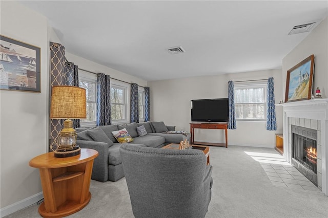 living room featuring a tile fireplace, visible vents, baseboards, and carpet