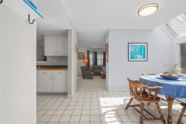 dining space with light tile patterned floors, baseboards, and light colored carpet