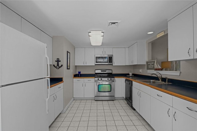 kitchen with dark countertops, stainless steel appliances, white cabinetry, and a sink