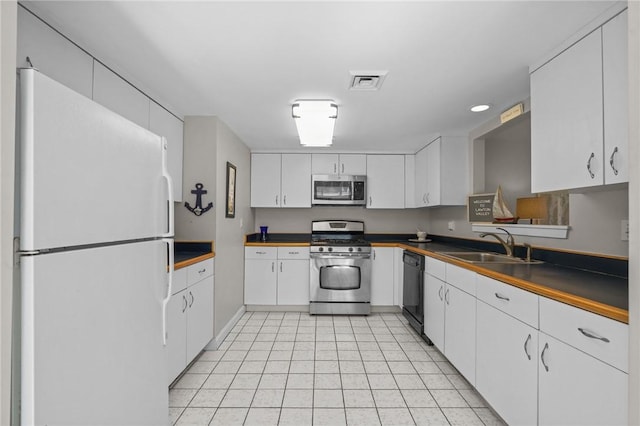 kitchen featuring dark countertops, a sink, white cabinetry, appliances with stainless steel finishes, and visible vents