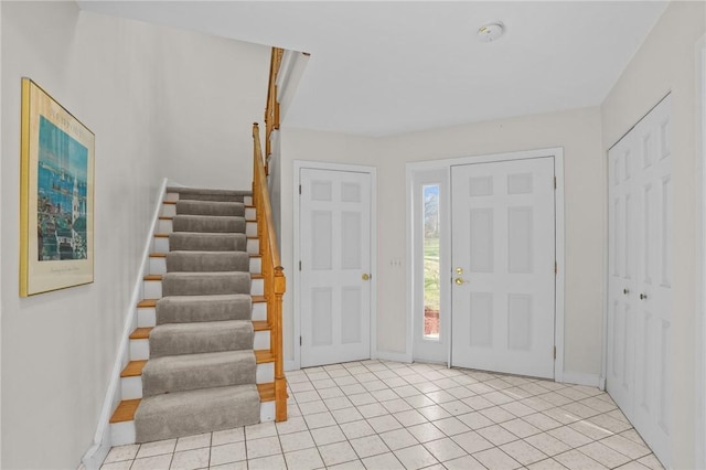 entryway featuring light tile patterned floors, baseboards, and stairway