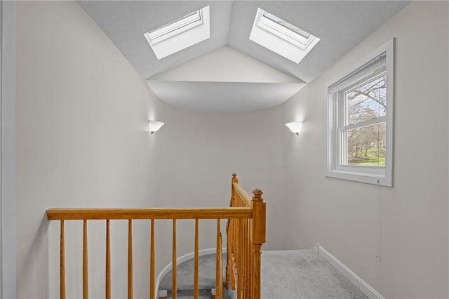 stairway with baseboards, carpet, and vaulted ceiling with skylight