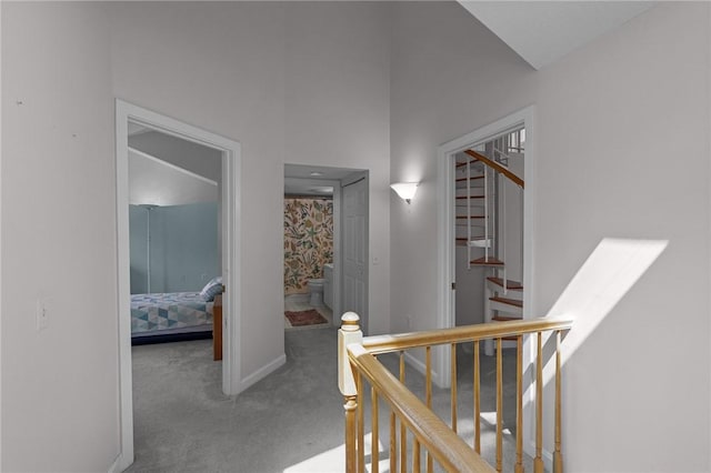 hallway with baseboards, carpet flooring, and stairway