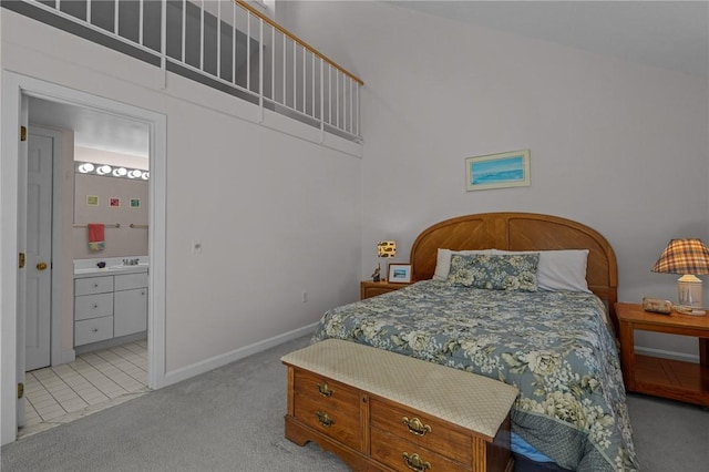 carpeted bedroom with ensuite bath and baseboards