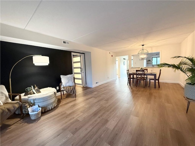 living room with baseboards, an inviting chandelier, a wealth of natural light, visible vents, and wood finished floors