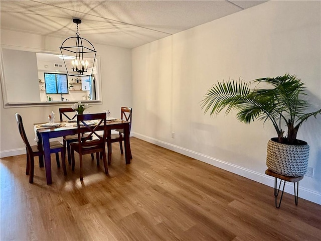 dining room with baseboards, a notable chandelier, and wood finished floors