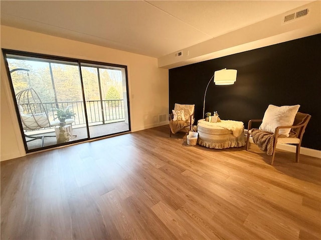 living area with wood finished floors, baseboards, and visible vents