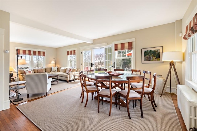 dining area featuring beamed ceiling, hardwood / wood-style floors, radiator heating unit, and baseboards
