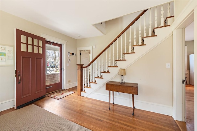 entryway with stairway, wood finished floors, and baseboards