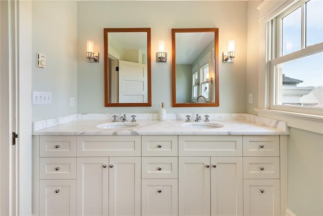 bathroom featuring a healthy amount of sunlight, double vanity, and a sink