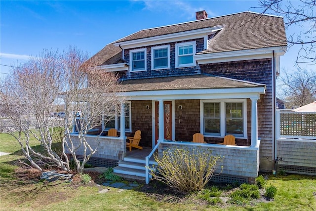 shingle-style home featuring a porch and a chimney
