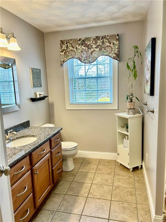 bathroom featuring tile patterned flooring, a wealth of natural light, toilet, and vanity