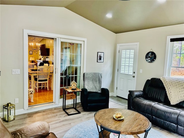 living room with a notable chandelier, vaulted ceiling, baseboards, and light wood-style floors