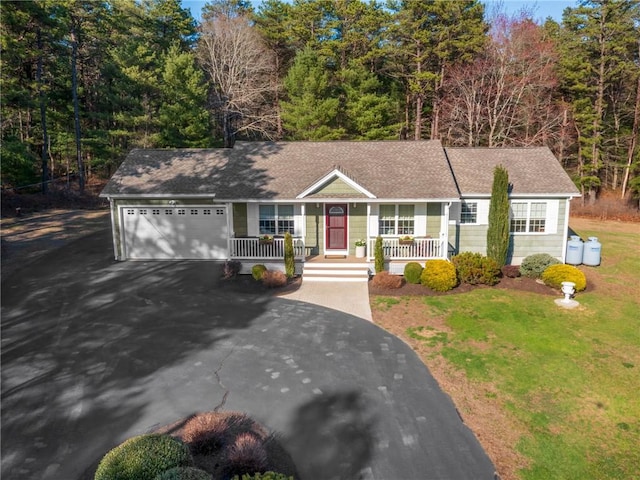 single story home featuring a shingled roof, driveway, covered porch, a front yard, and a garage
