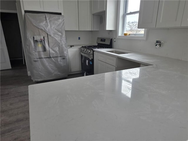 kitchen featuring light stone countertops, dark wood-style floors, gas range, white cabinets, and fridge with ice dispenser