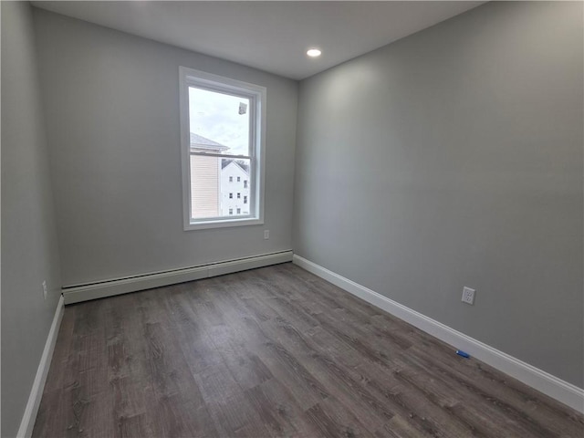 unfurnished room featuring baseboards, baseboard heating, and wood finished floors
