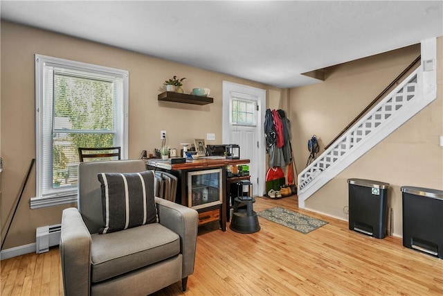 living area featuring baseboards, baseboard heating, stairway, and hardwood / wood-style flooring