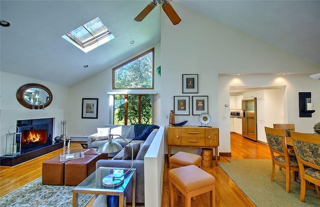 21 Fesser Ave, Bristol, RI 02809 - living area with high vaulted ceiling, a baseboard radiator, a skylight, a warm lit fireplace, and light wood finished floors
