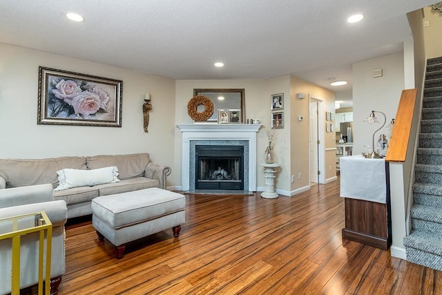 living area featuring stairway, a fireplace with flush hearth, wood finished floors, and recessed lighting