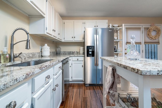 kitchen featuring appliances with stainless steel finishes, light stone countertops, a sink, and white cabinetry
