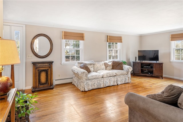 living area featuring a baseboard heating unit, light wood-style flooring, baseboards, and ornamental molding