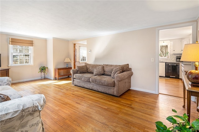 living area with baseboards, ornamental molding, and light wood-type flooring