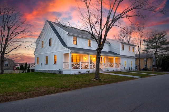 view of front of house featuring board and batten siding, a lawn, a porch, and roof with shingles