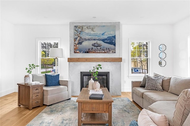 living room with baseboards, a high end fireplace, and light wood-style flooring