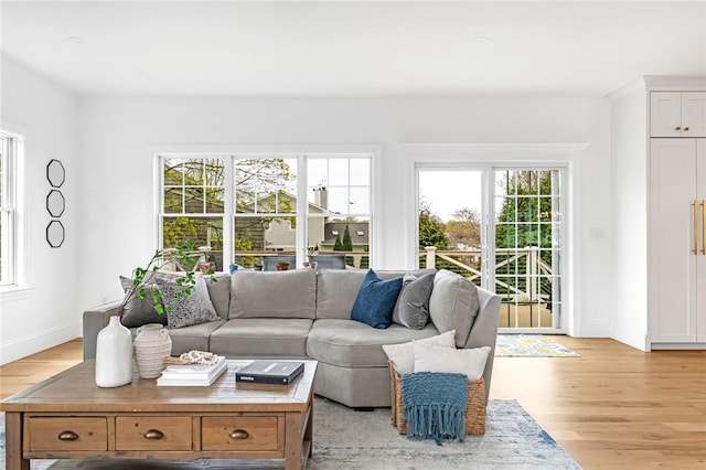 living room featuring baseboards, plenty of natural light, and light wood finished floors