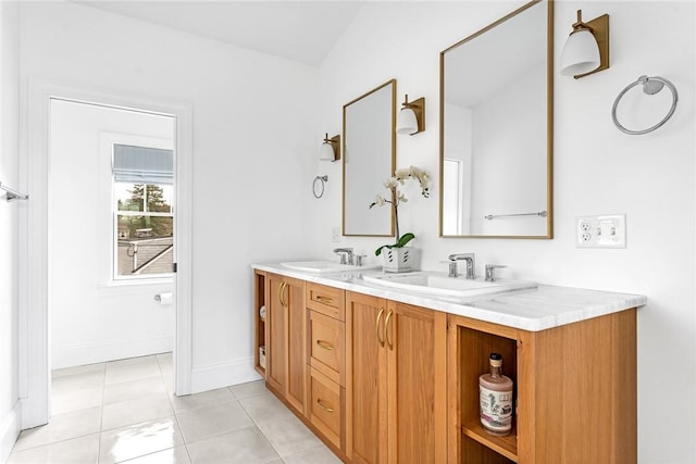 bathroom featuring double vanity, a sink, baseboards, and tile patterned floors
