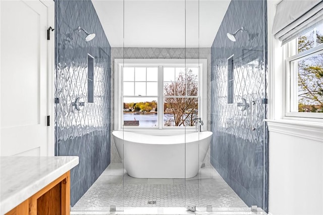 full bathroom featuring a freestanding bath, vanity, a stall shower, and tile walls