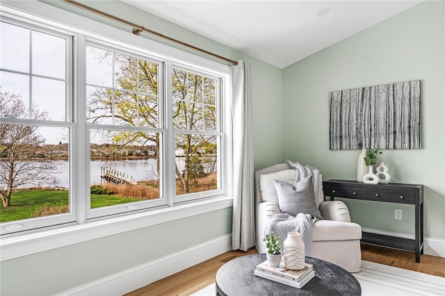 sitting room with a water view, plenty of natural light, and wood finished floors