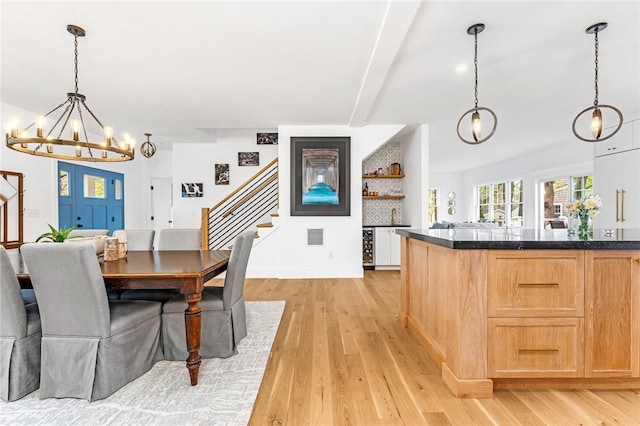 dining room featuring light wood finished floors, beam ceiling, a chandelier, and stairway