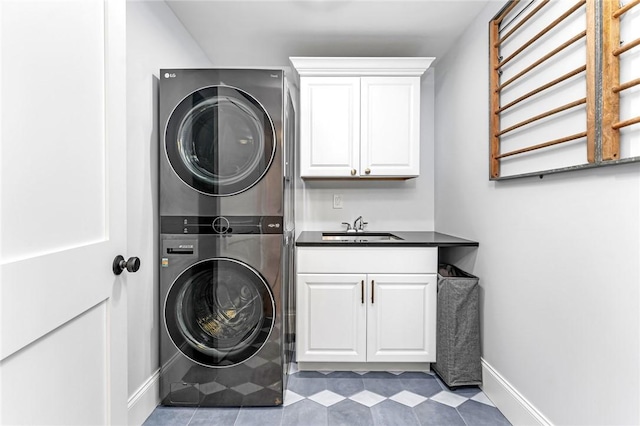 laundry area with baseboards, tile patterned floors, a sink, cabinet space, and stacked washer / drying machine