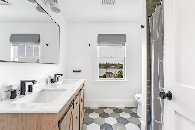 full bath with baseboards, double vanity, tile patterned floors, and a sink