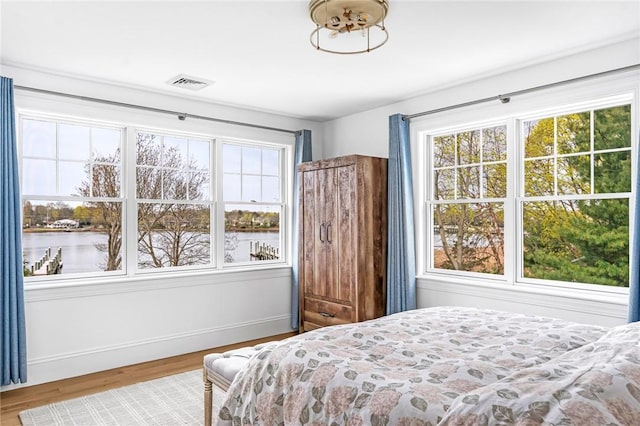 bedroom with baseboards, multiple windows, wood finished floors, and visible vents