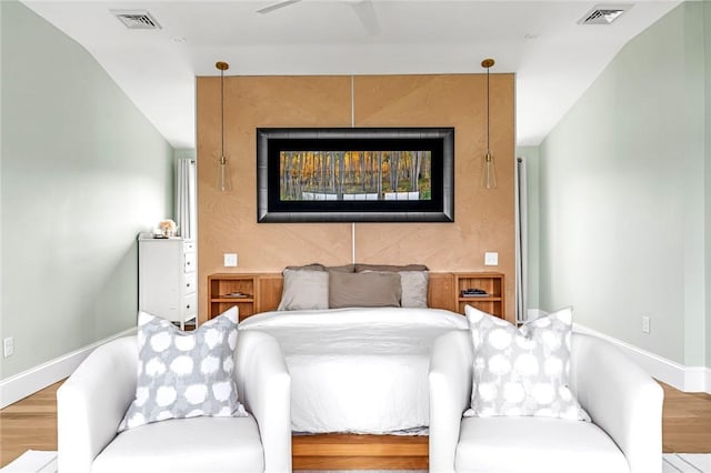 bedroom with visible vents, baseboards, and wood finished floors