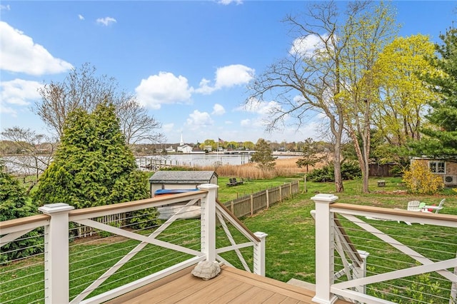 wooden terrace featuring a storage shed, a lawn, and an outbuilding