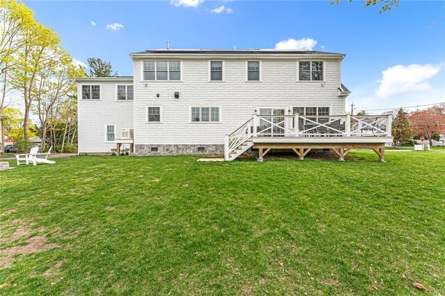 rear view of property featuring a lawn, a deck, and crawl space