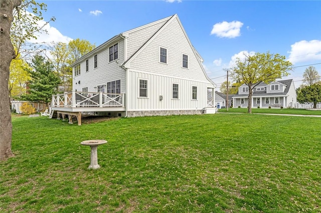 back of house with board and batten siding, a deck, and a yard