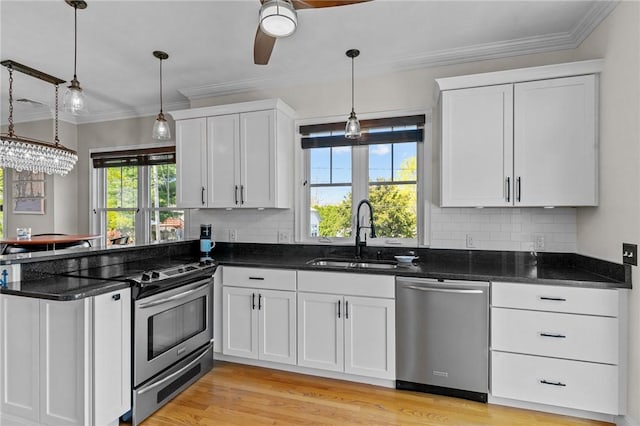 kitchen featuring tasteful backsplash, a sink, stainless steel appliances, a peninsula, and white cabinetry