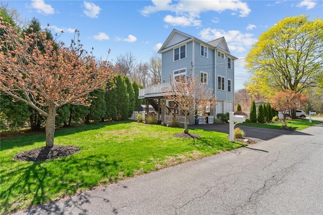 view of front of property with driveway, a deck, and a front yard