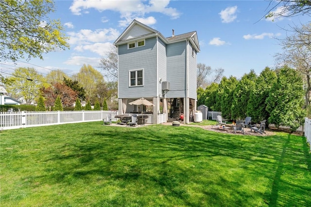 back of property with a fenced backyard, a yard, a patio, and an outdoor fire pit